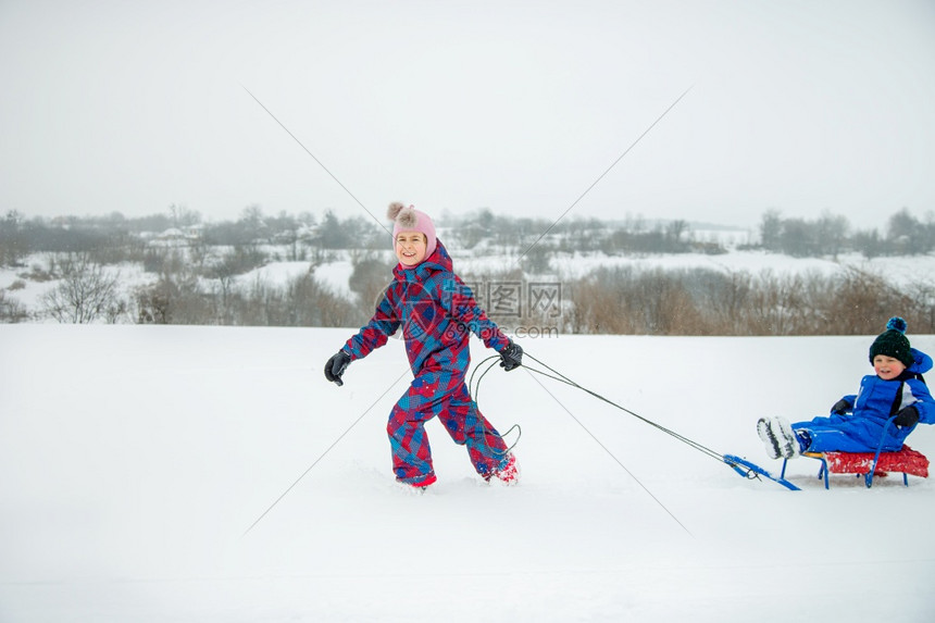 快乐的男孩和女在冬天从山上拉雪橇冬季户外运动会寒假冬季户外运动会公园冷冻周末图片