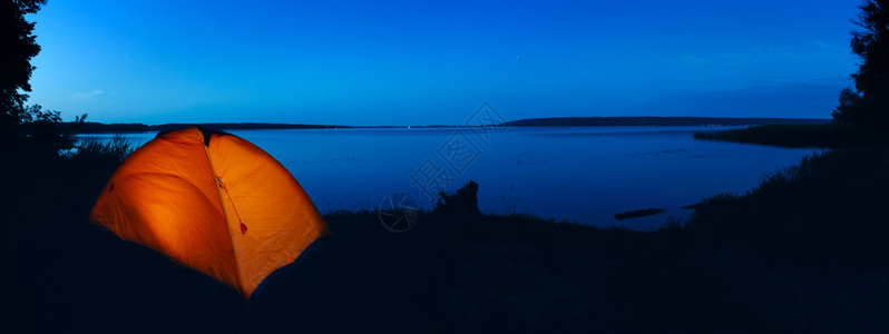 夜间天空全景隐私旅行与和谐的概念湖上橙色轻便帐篷湖上橙色轻薄帐篷发光的草水图片