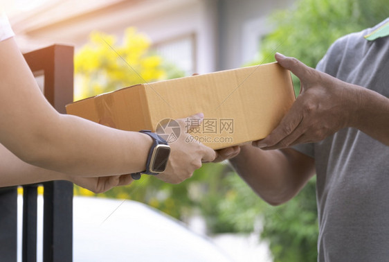 邮递员在家门口从送货员那里接收包裹盒的年轻女近身手男人顾客图片