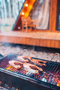 周末烧烤炉上的鱼牛排火焰和烟雾卷在鱼的碎片上BBQ鱼牛排鲑肉片在大火中被炸天炉排图片