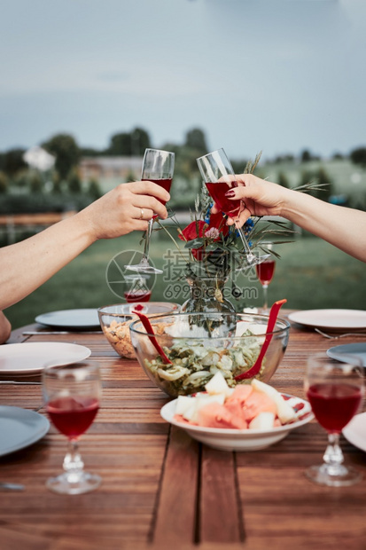 在夏季户外晚宴期间在家庭花园里做烤面包的情侣手拿着红酒杯和以及盘子派对女士保持图片