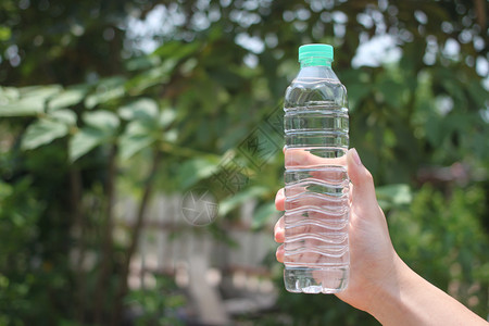 男人的手在花园里拿着一瓶饮用水并给你复制空间笑声健康散景人类图片