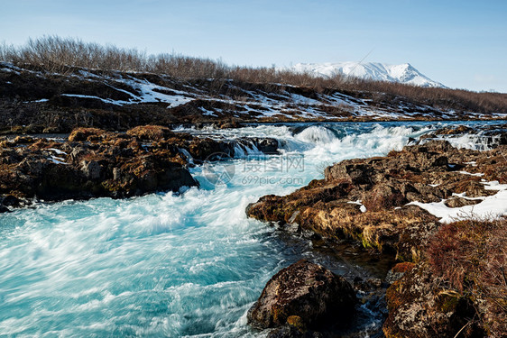 雪在阳光明媚的一天冰岛Midfos瀑布冰岛河Midfos瀑布颜色结石图片