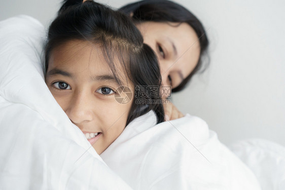 爱的肖像家人母亲和女儿拥抱在一起可爱的女孩微笑着美丽快乐的床上笑天人们女士图片