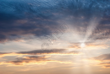 明亮的多云橙天空与圆穿透太阳的光线在云中穿透太阳的光线穿过云图片