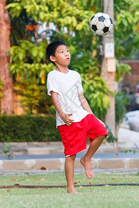 喜悦喘气行动在花园踢足球的泰国男孩图片