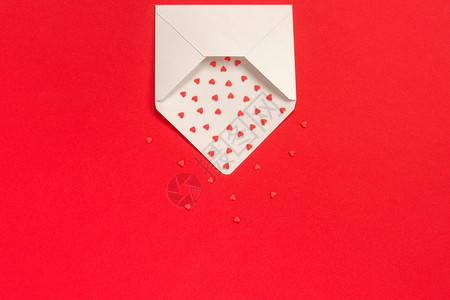 红色糖果洒心飞出白纸信封位于红色背景顶部视图复制文本空间概念情人节和卡片礼物带有爱的消息红色糖果洒心飞出红色背景上的白皮书信封顶背景图片