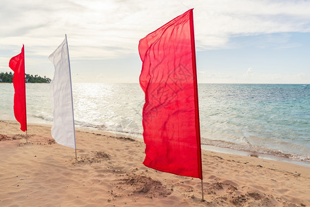 日落时沙滩上的红旗和白旗图片