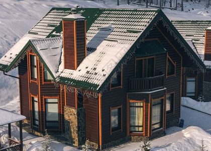 传统的家白色在滑雪度假胜地冬时在椰林附近被雪覆盖的Wooden舒适小屋图片