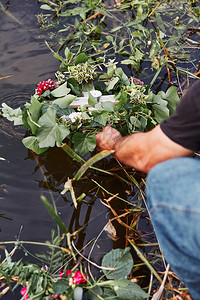 自然湖真实的鲜花和草药环男子从河中取花环仲夏占卜图片