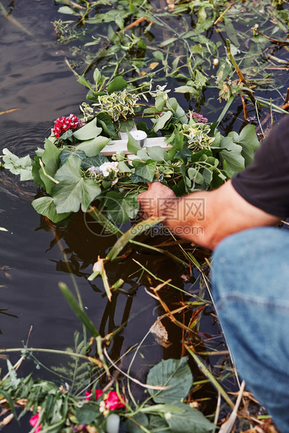 自然湖真实的鲜花和草药环男子从河中取花环仲夏占卜图片