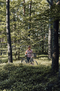 景观活跃的女在森林里骑自行车度过免费暑假戴着自行车头盔和手套的女拿着带篮子的自行车娱乐趣图片