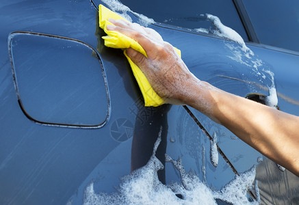 闪耀肮脏的用黄海绵洗灰色汽车女用肥皂泡沫洗手机用黄色海绵洗灰汽车雨刮器图片