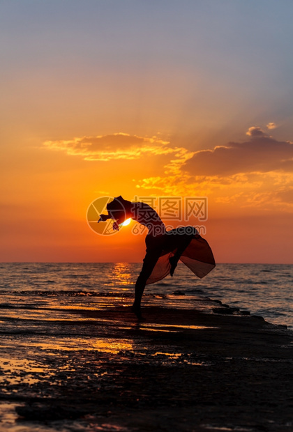 海边夕阳下跳舞的女性图片