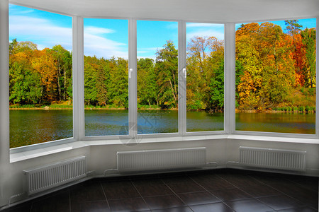 带窗户的房间可以看到秋天的森林和湖泊秋天的风景和森林中湖泊从房间窗户可以看到大自然的全景从窗户可以看到彩色的秋天树木的风景内部户图片