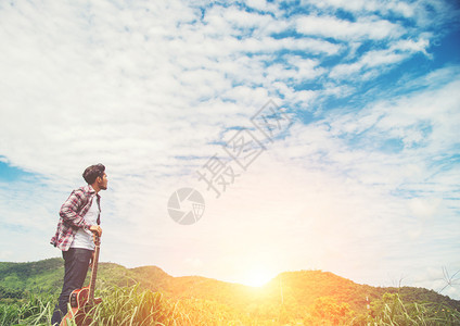 音乐草带着吉他和自然行走的年轻嬉皮士男子RelYounghistster男子拿着吉他与自然行走的在阳光明媚的蓝天在田里放松一种图片