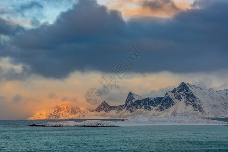 诺德兰挪威冬季海洋的荒山区岸厚云和阳光与在挪威湾冬季上空照耀日光多山全景图片