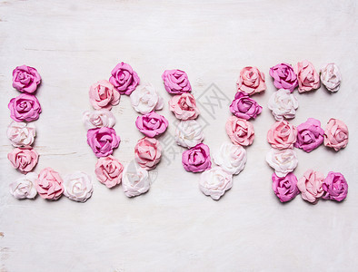 由纸玫瑰华伦人节装饰品制作的爱情字词在木制白色生锈背景顶端近处为了象征粉色的图片