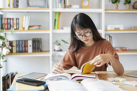 在书架前阅读的戴眼镜女孩图片