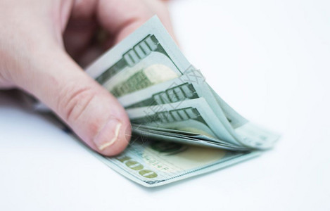 收益人在白色背景上数一叠10美元的国纸币数交换图片
