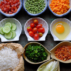 亚洲晒干绿色越南食物炒饭大米鸡蛋香肠干虾豆黄瓜番茄胡萝卜和扇菜用木制的多彩食品加工图片