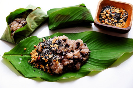高的黏越南人自制黑豆粘糊米配有芝麻盐在白底竹子篮上以绿色叶快速早餐染色图片