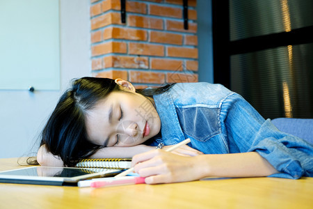学习女孩累在办公桌与文件一起工作时睡得精疲力尽的年轻女亚洲学生午睡在读书后休息教育加班在家工作等概念下亚洲女学生图片