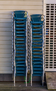茅草阳台餐饮业的闭锁轮式百叶窗旁边的堆叠椅积累图片