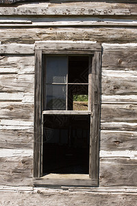 在一个古老的风湿谷仓窗户上周围布满了粗糙的木板在另一边有从些丢失的玻璃杯中看到一面请注意这些年建筑和窗框都略微受到质疑经过沃尔德图片