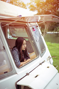 露营车假期年轻的夏日坐在野营车里的美丽年轻女士图片