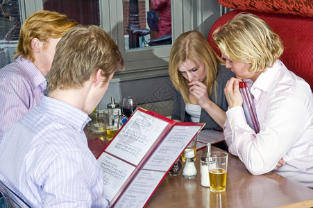 调味品菜肴一组由四人成在一家餐馆里从菜单中挑选盘饮料图片