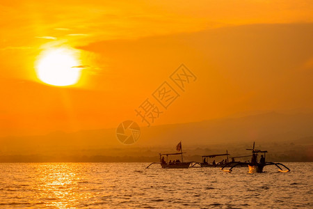 天空传统的印度尼西亚在巴厘河沿岸海域黎明时正在等待海豚Balinese船在黎明时出现海洋中橙背景图片
