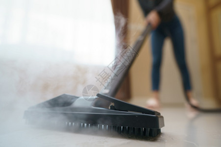 打扫清洁度电的女人用蒸汽拖把洗地板图片