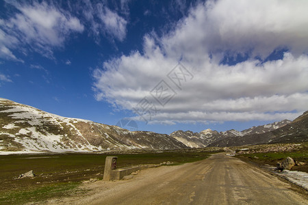 冰川全景雪地山上一片阴云的天空和高地道路谷图片