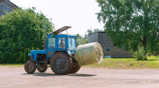 季节天空卡车农机拖上的稻草卷拖拉机运输绞捆干草拖拉机传输绞捆干草农机拖车中的稻草卷图片