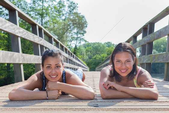 两名青年妇女躺在木桥上身处自然界的木桥上自由天幸福图片
