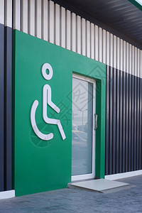 地面白色残疾人轮椅标志绿色墙上有玻璃门公共厕所区侧视和垂直架子有木板壁装饰的绿墙和木板壁垂直的白色图片