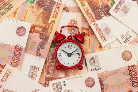 现金俄罗斯千分之五钞票背景上的红色闹钟概念时间就是金钱俄罗斯千分之五钞票背景上的红色闹钟概念时间就是金钱经济的成功图片