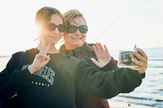 暑假旅行时妇女在用视频电话打智能手机时做出势和挥并拍自照片沟通笑社会的图片