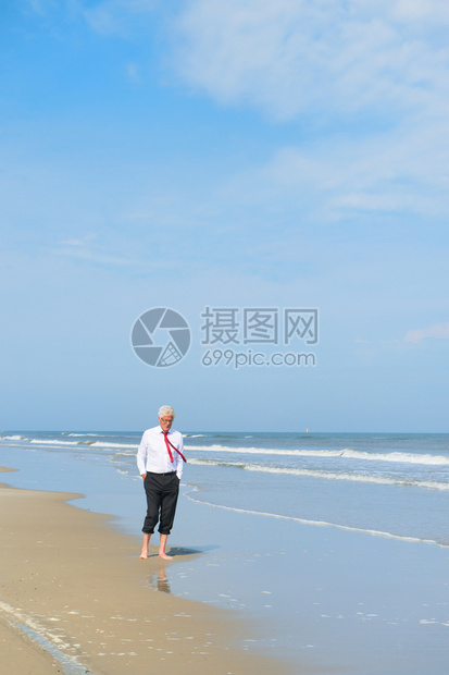 北穿正式西装的商人在海滩散步景观夏天图片