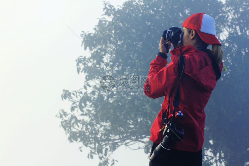 照片摄影师远足妇女穿着红色衬衫站在拍照着图片