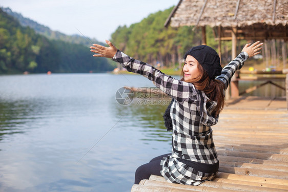 水坐在码头上的女人看着日落的美丽坐图片