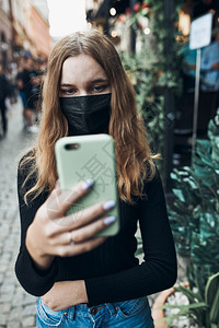 穿年轻女子在市中心步行时带着面罩通过视频电话交谈以避免感染防止疾病在出现冠状腺毒时传播她们戴着面罩以避免感染和预防疾的传播保护关图片