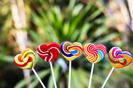 浪漫的甜点糖心形状在模糊背景上满的颜色彩虹棒糖的果情人节礼物爱的概念卡片图片