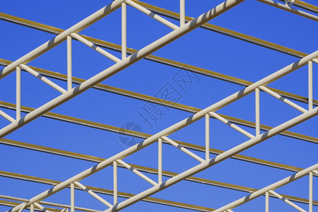 工厂外部的不完整蓝色天空背景下建筑区黄金属屋顶结构的低角和对视图以蓝天背景为基准图片