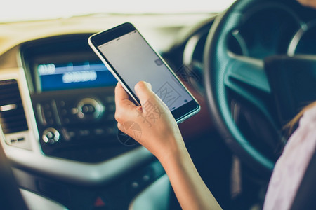 细胞坐着亚裔妇女在路上驾驶汽车使用智能手机在路上沟通图片
