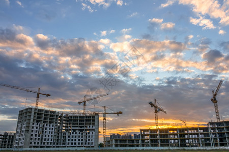 黄昏现代的建造住宅楼夏季阴云笼罩许多起重机正在运行中建筑起重机和夜云系统CraimCranes和CreenClouds工人图片