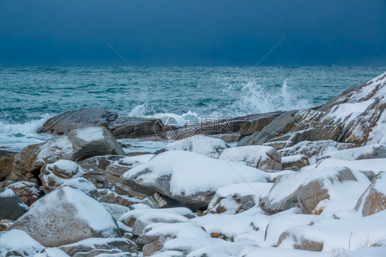 海景溅冰雪覆盖的岩石海岸寒冬早期天空覆盖在地平线上的重天顶冰封石块北图片