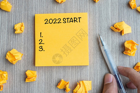快乐的使命概念新年决议战略和目标概念新年由商人拿笔和木桌背景纸折碎写在木桌背景战略及目标概念上图片