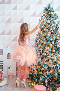 快乐的服务可爱女孩在室内装饰圣诞树快乐树附近的漂亮女孩装饰欧洲的图片